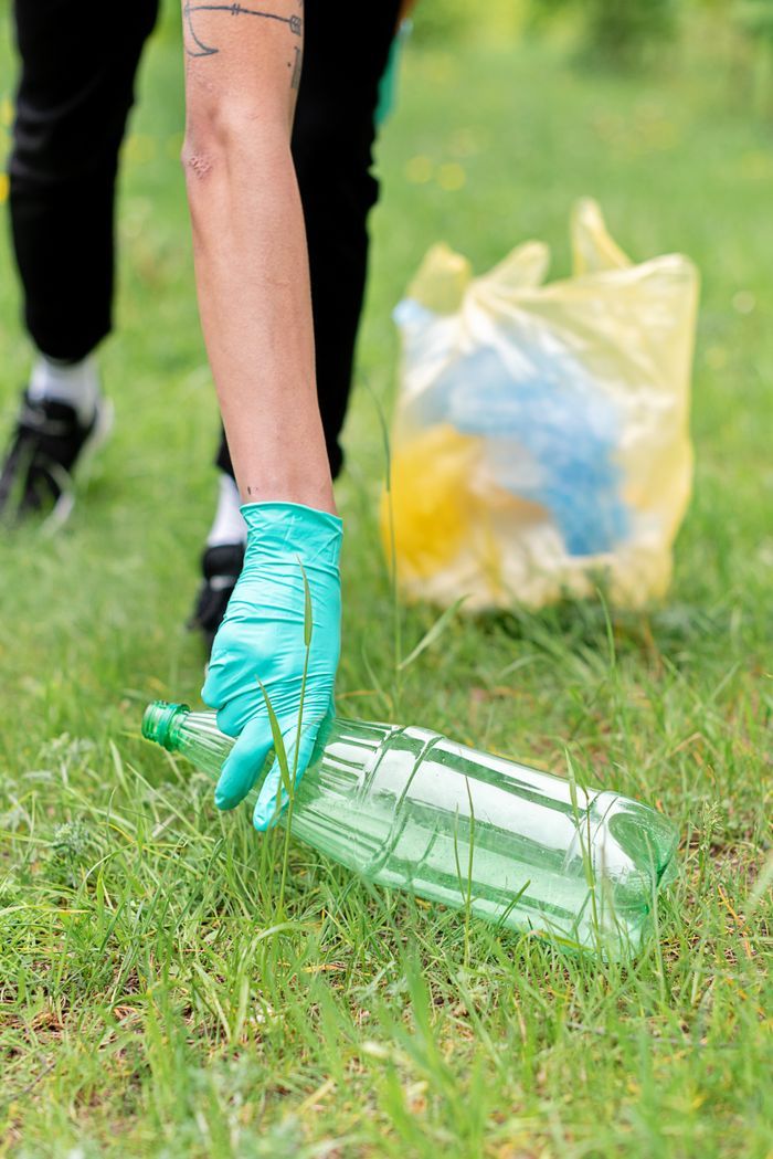 Crafting Captivating Headlines: Your awesome post title goes here Close-up of a person wearing gloves collecting litter in a grassy area, promoting recycling.